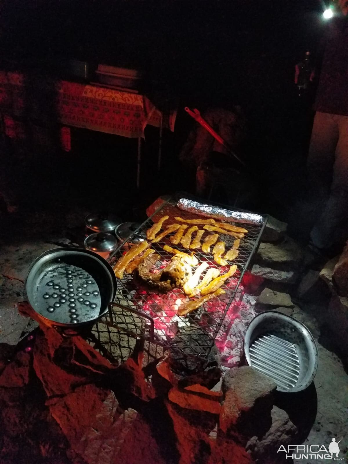 Tenderloin of beef, marinated bacon strips, sausage and garlic bread (foiled) over the fire.